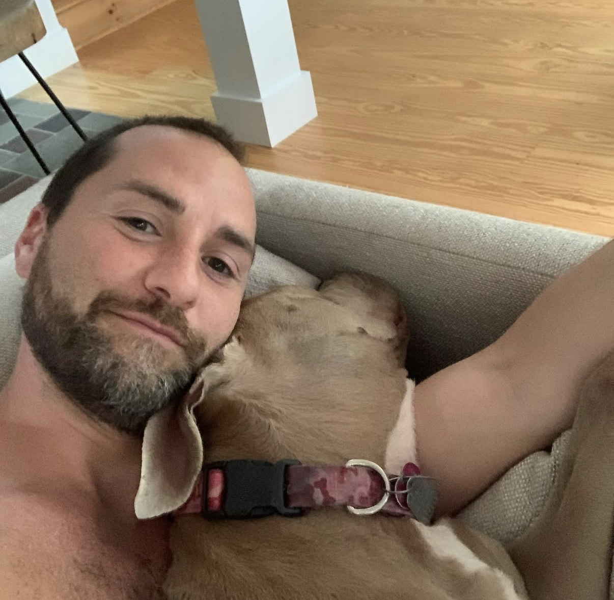 Shaul resting on the couch with Luna curled up beside him